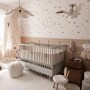 Delikatna tapeta w różowe kwiatki nad łóżeczkiem niemowlęcym w eleganckim pokoju dziecka