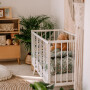 Białe drewniane łóżeczko niemowlęce ze szczebelkami