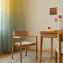 Drewniany, dębowy fotel w stylu skandynawskim z jasną, beżową tapicerką typu plecionka, z domieszką naturalnych włókien.