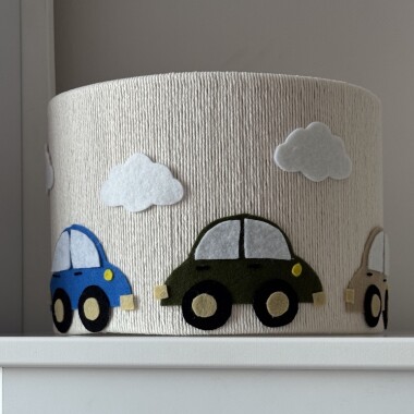 Lampa sufitowa ze sznurka w kremowym kolorze z trzema autkami i białymi chmurkami z filcu.