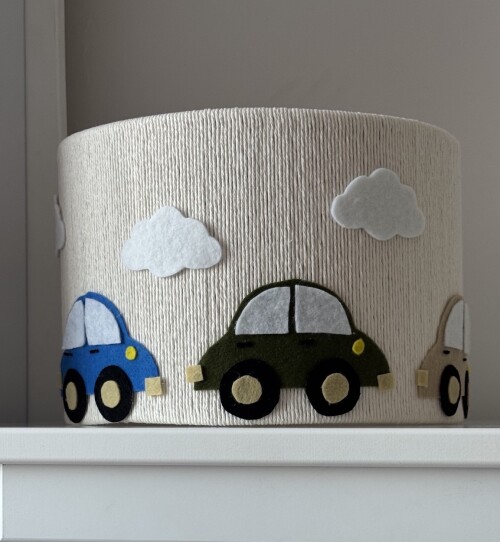 Lampa sufitowa ze sznurka w kremowym kolorze z trzema autkami i białymi chmurkami z filcu.