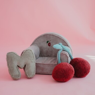 Sztruksowy mały fotelik dla małego dziecka lub starszego niemowlaka. Na foteliku wyhaftowana jest śliwka